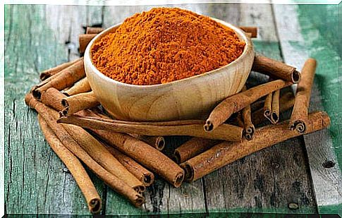 Bowl of crushed cinnamon on a wooden table with cinnamon sticks