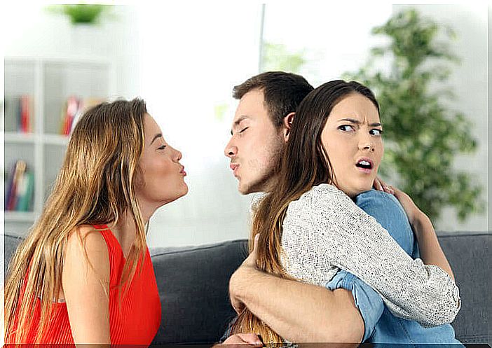 A man hugs a woman while trying to kiss another woman behind her back