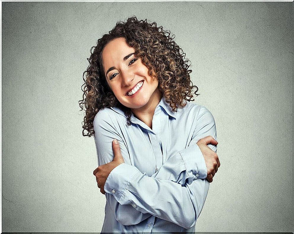 Woman smiling and hugging herself