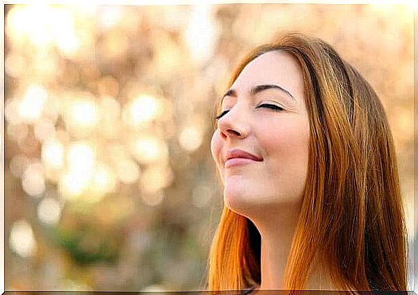 Woman standing with closed eyes and smiling