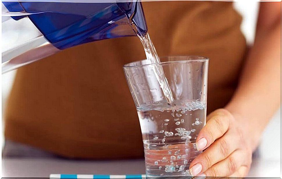 Person pours water into glass from jug