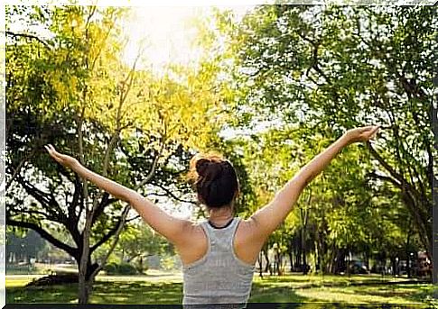 Grounding is a practice that prescribes increasing your connection to nature to promote your well-being that this woman in the park exercises