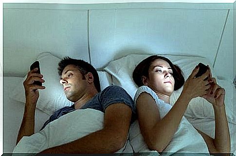 Couple lying in bed with their mobiles