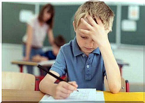 Boy in classroom takes headache due to migraine in children