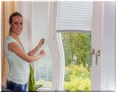 Woman by blinds smiling