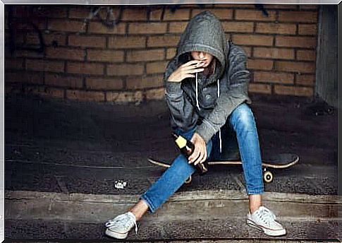 Person with cigarette in mouth sitting on skateboard