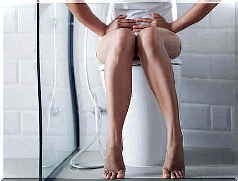 Woman sitting on toilet with stomach ache